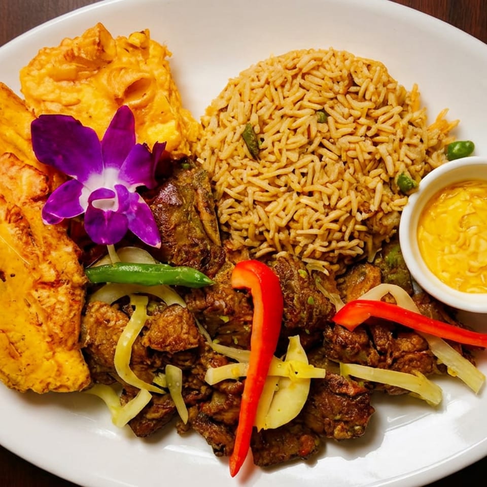 A vibrant dish with rice, meat, plantains, and a purple orchid garnish on a white plate.